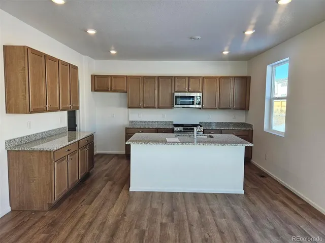 a large kitchen with stainless steel appliances granite countertop a stove a sink a refrigerator and a cabinets