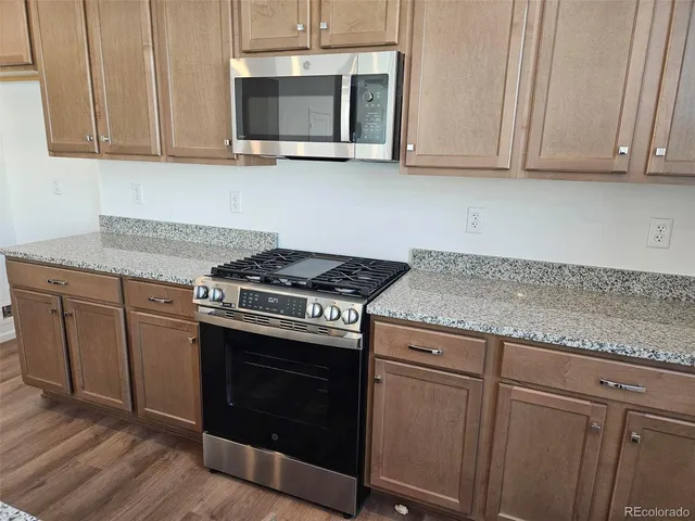 a kitchen with granite countertop cabinets stainless steel appliances and wooden floor