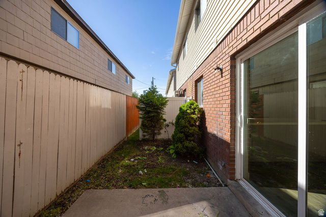 283 West 600 North, Unit 2 Logan, UT 84321 - Photo 7 of 36 Concrete patio area with a sliding glass door entry, brick facade, and vinyl siding