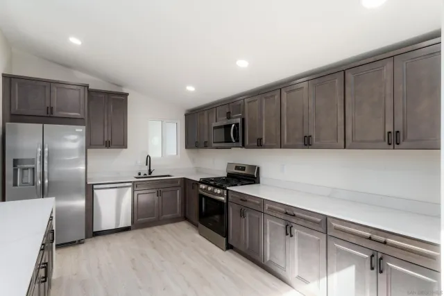 a kitchen with stainless steel appliances a sink a stove a refrigerator cabinets and a counter top space