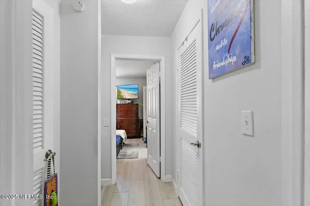 a view of a hallway with closet and a bathroom