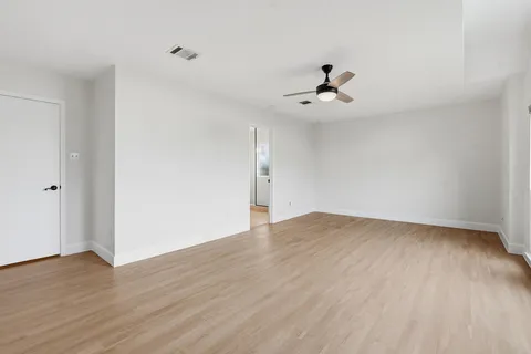 an empty room with wooden floor ceiling fan and windows