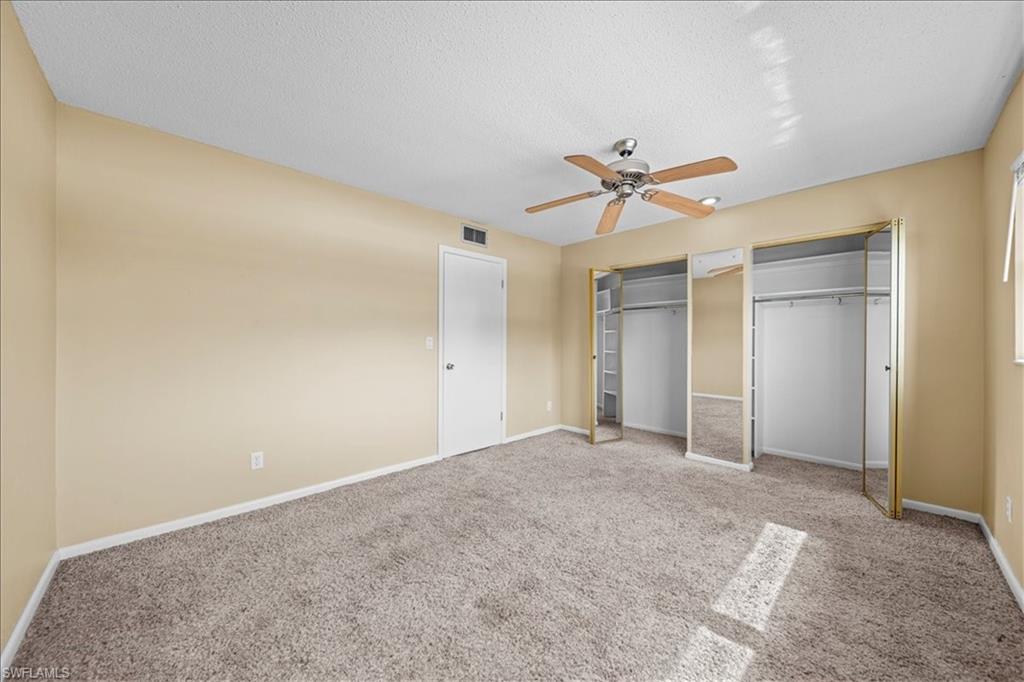 3225 East Riverside Drive, Unit 17A Fort Myers, FL 33916 - Photo 16 of 30 Unfurnished bedroom featuring carpet floors, multiple closets, a textured ceiling, and ceiling fan