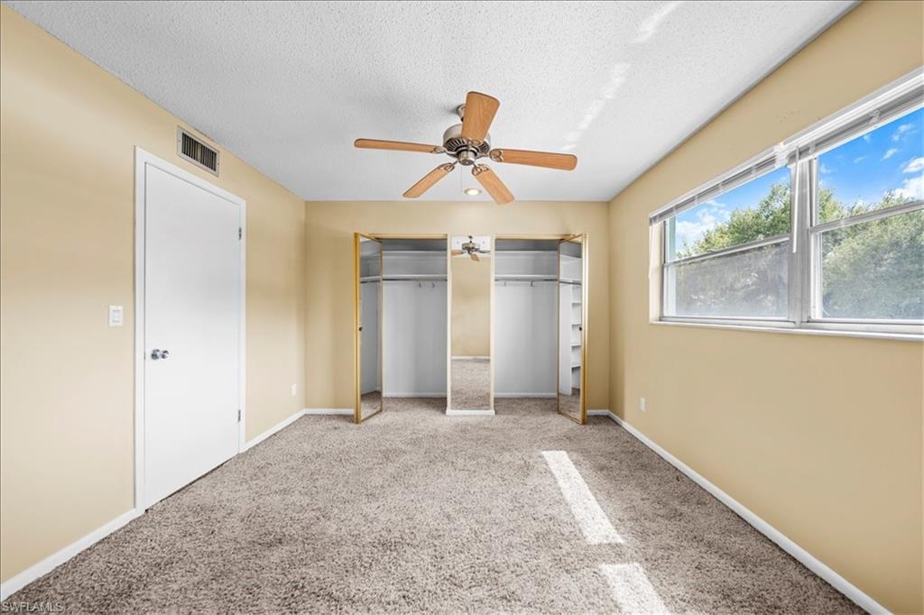 3225 East Riverside Drive, Unit 17A Fort Myers, FL 33916 - Photo 17 of 30 Unfurnished bedroom with two closets, carpet flooring, a textured ceiling, and a ceiling fan