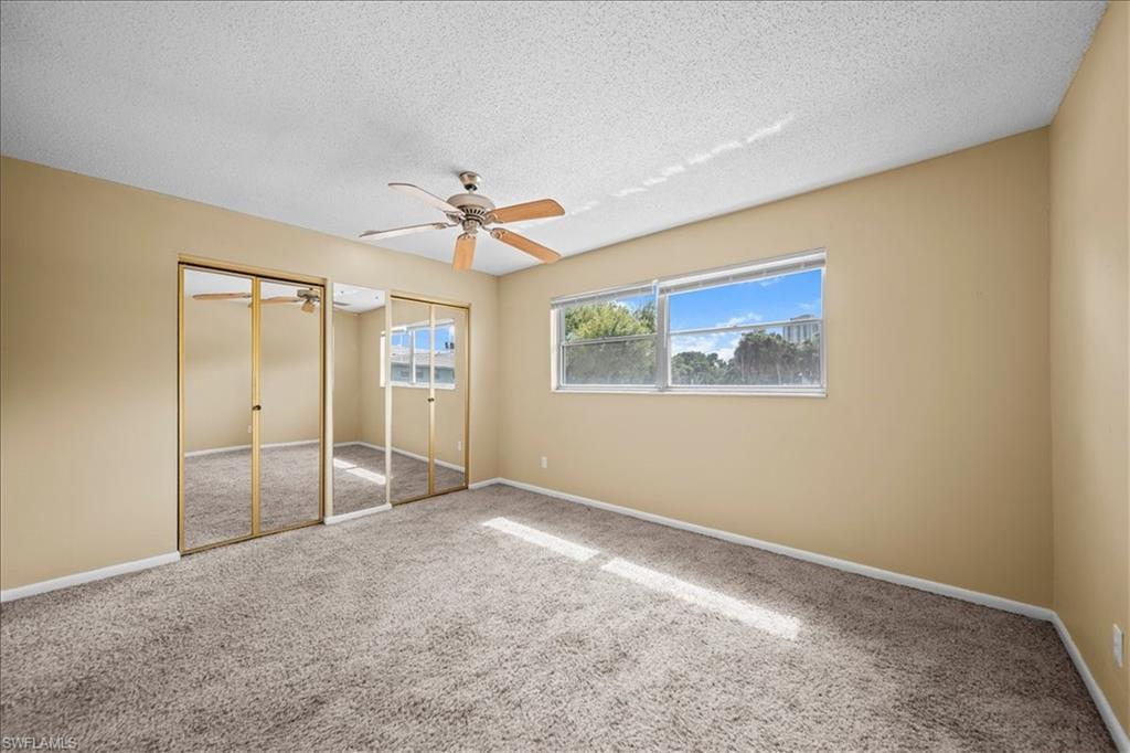 3225 East Riverside Drive, Unit 17A Fort Myers, FL 33916 - Photo 18 of 30 Unfurnished bedroom featuring two closets, carpet floors, ceiling fan, and a textured ceiling