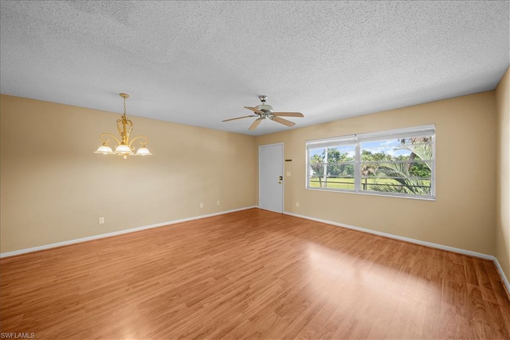 3225 East Riverside Drive, Unit 17A Fort Myers, FL 33916 - Photo 2 of 30 Unfurnished room with a chandelier, light wood finished floors, a textured ceiling, and ceiling fan
