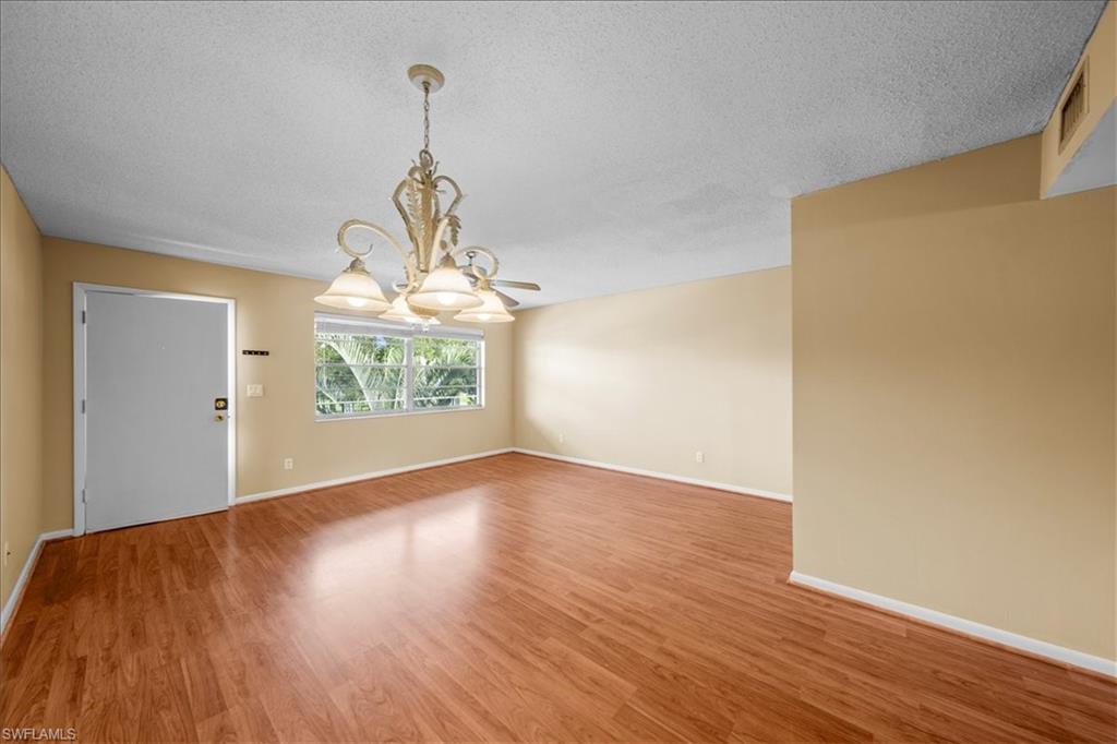 3225 East Riverside Drive, Unit 17A Fort Myers, FL 33916 - Photo 5 of 30 Unfurnished room with a textured ceiling, light wood-style flooring, and a chandelier