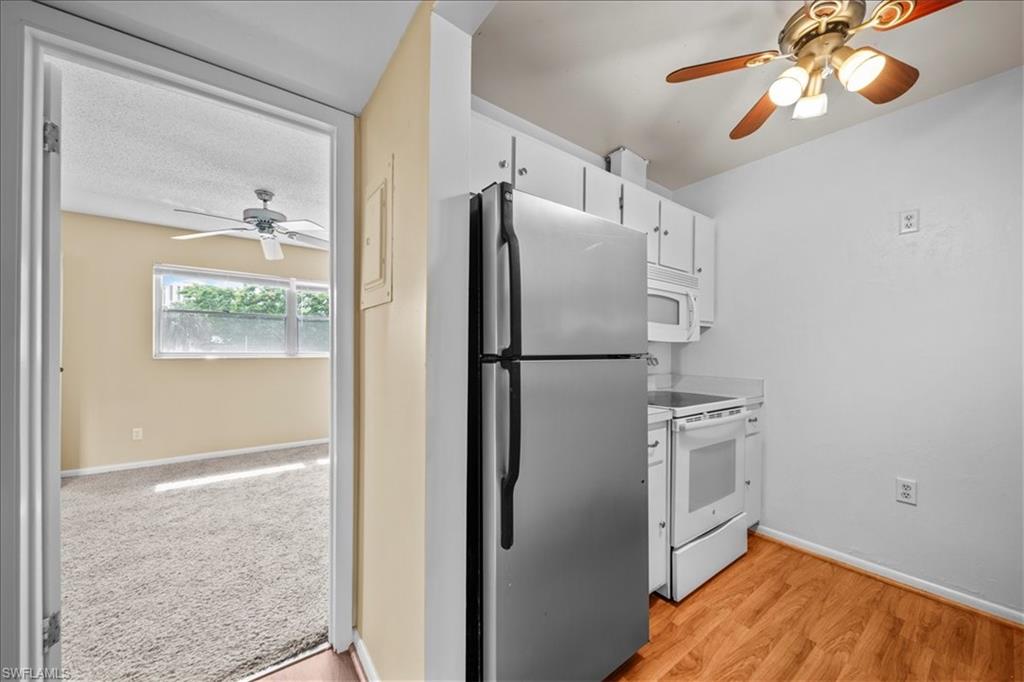 3225 East Riverside Drive, Unit 17A Fort Myers, FL 33916 - Photo 8 of 30 Kitchen featuring a ceiling fan, white appliances, light countertops, white cabinets, and light wood-style flooring