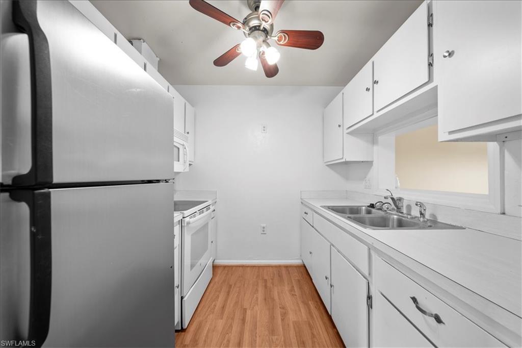 3225 East Riverside Drive, Unit 17A Fort Myers, FL 33916 - Photo 9 of 30 Kitchen featuring white appliances, white cabinetry, light countertops, and light wood-type flooring