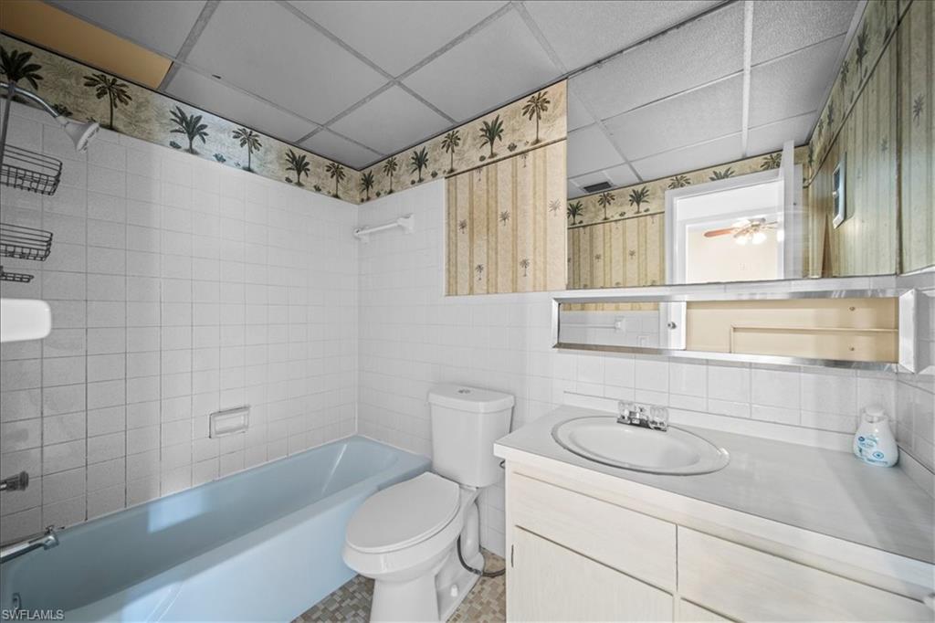 3225 East Riverside Drive, Unit 17A Fort Myers, FL 33916 - Photo 10 of 30 Full bath with shower combination, a drop ceiling, vanity, tile walls, and backsplash