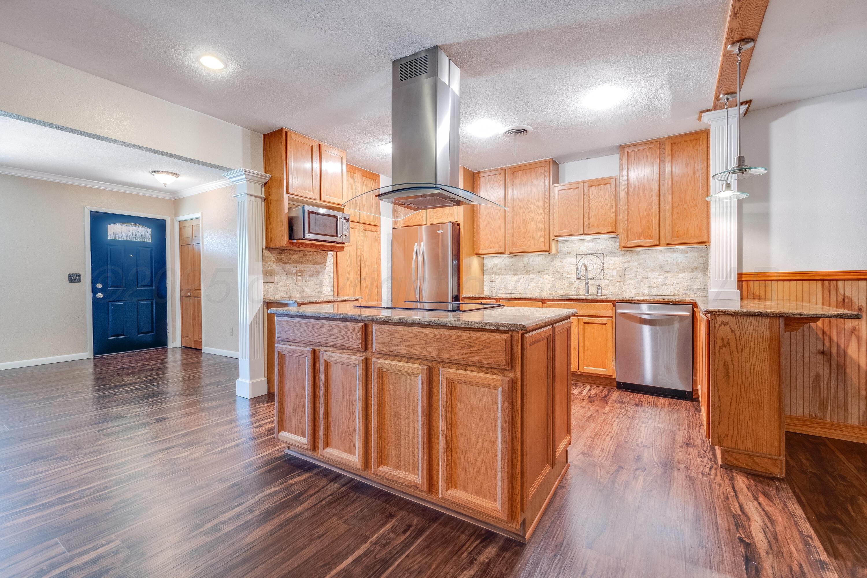 2401 Darrell Avenue Amarillo, TX 79110 - Photo 4 of 35 a kitchen with stainless steel appliances granite countertop a refrigerator a sink dishwasher a stove and white countertops with wooden floor