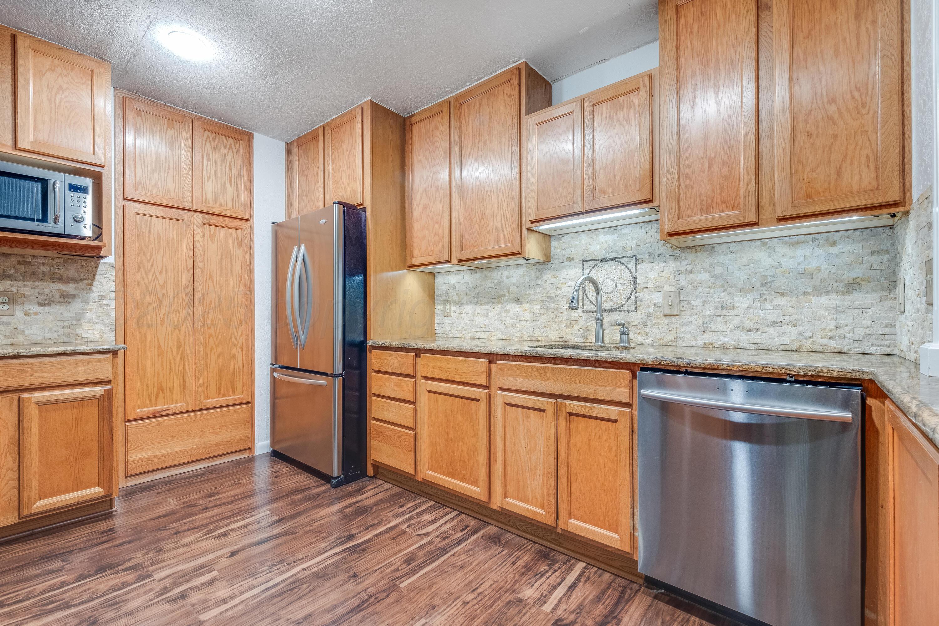 2401 Darrell Avenue Amarillo, TX 79110 - Photo 5 of 35 a kitchen with stainless steel appliances granite countertop wooden cabinets a refrigerator and sink