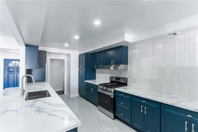 a kitchen with stainless steel appliances granite countertop a stove a sink and a refrigerator