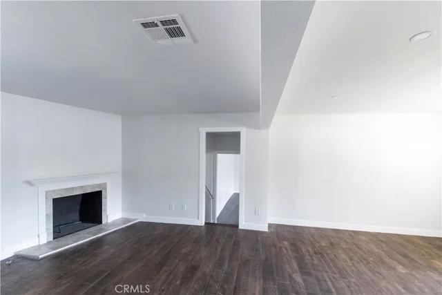 a view of an empty room with wooden floor and a fireplace