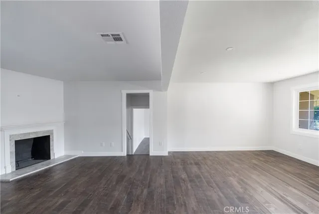 a view of empty room with wooden floor and fireplace