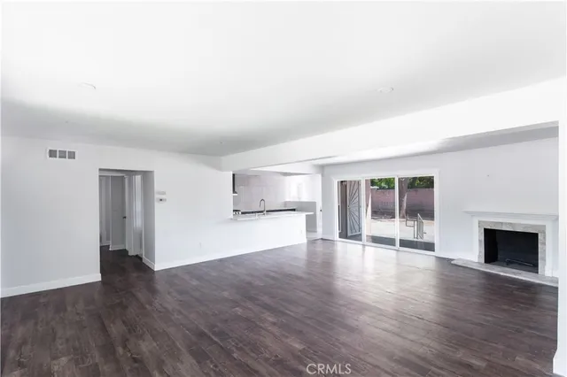 an empty room with wooden floor fireplace and windows