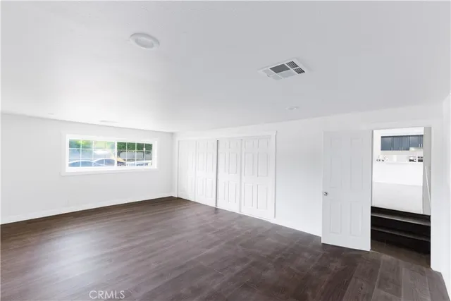 an empty room with wooden floor cabinet and ceiling fan