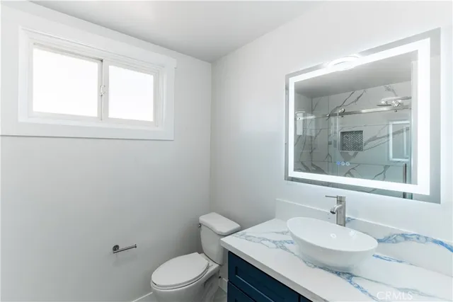 a bathroom with a sink vanity mirror and toilet