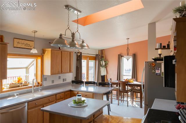 8115 Mustang Road Colorado Springs, CO 80908 - Photo 16 of 48 Kitchen with appliances with stainless steel finishes, hanging light fixtures, light countertops, a center island, and a peninsula