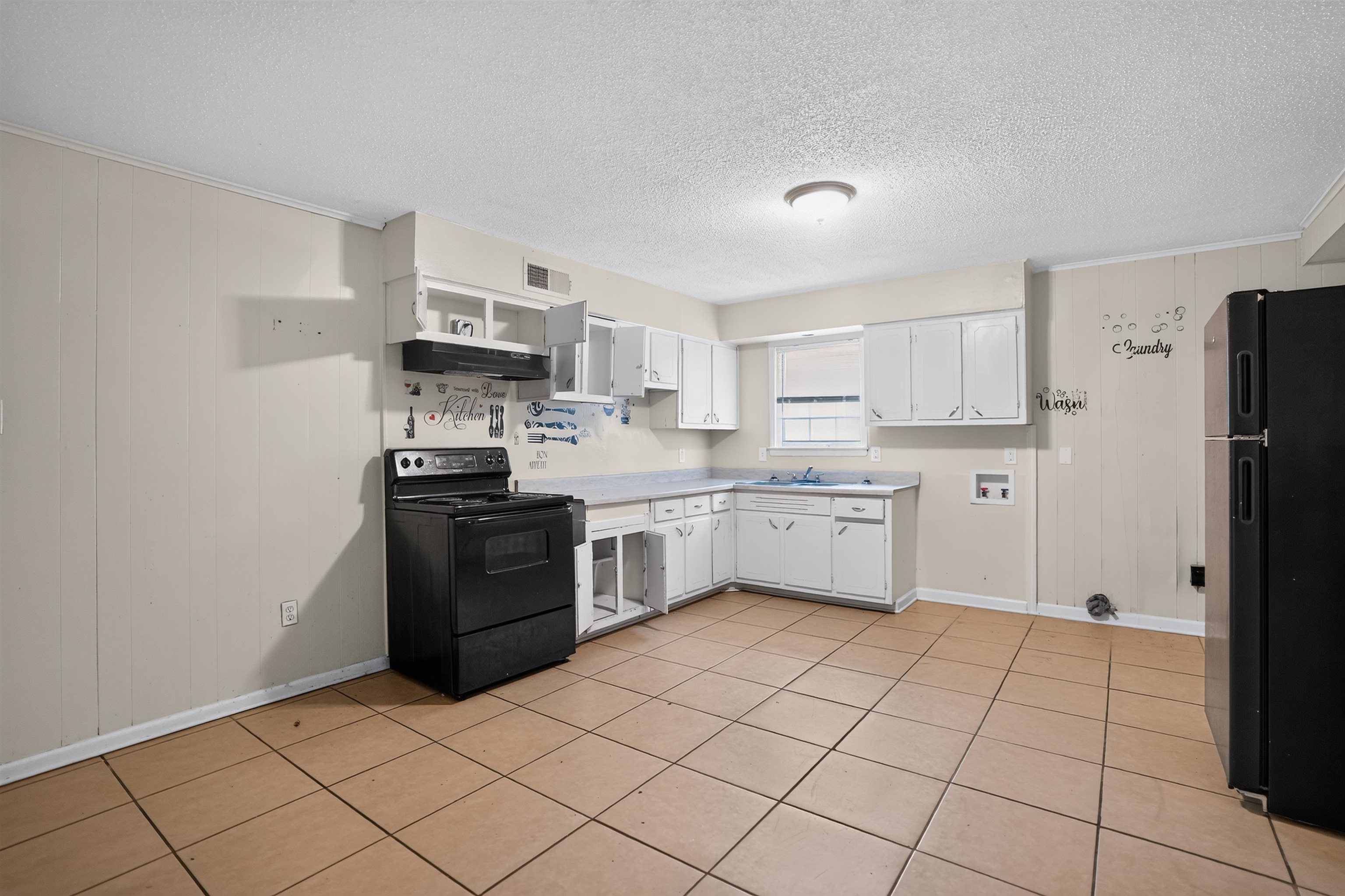 3736 Range Line Road Memphis, TN 38127 - Photo 10 of 18 Spacious kitchen area featuring tile flooring, white cabinetry, a black range with an overhead hood, and a black refrigerator