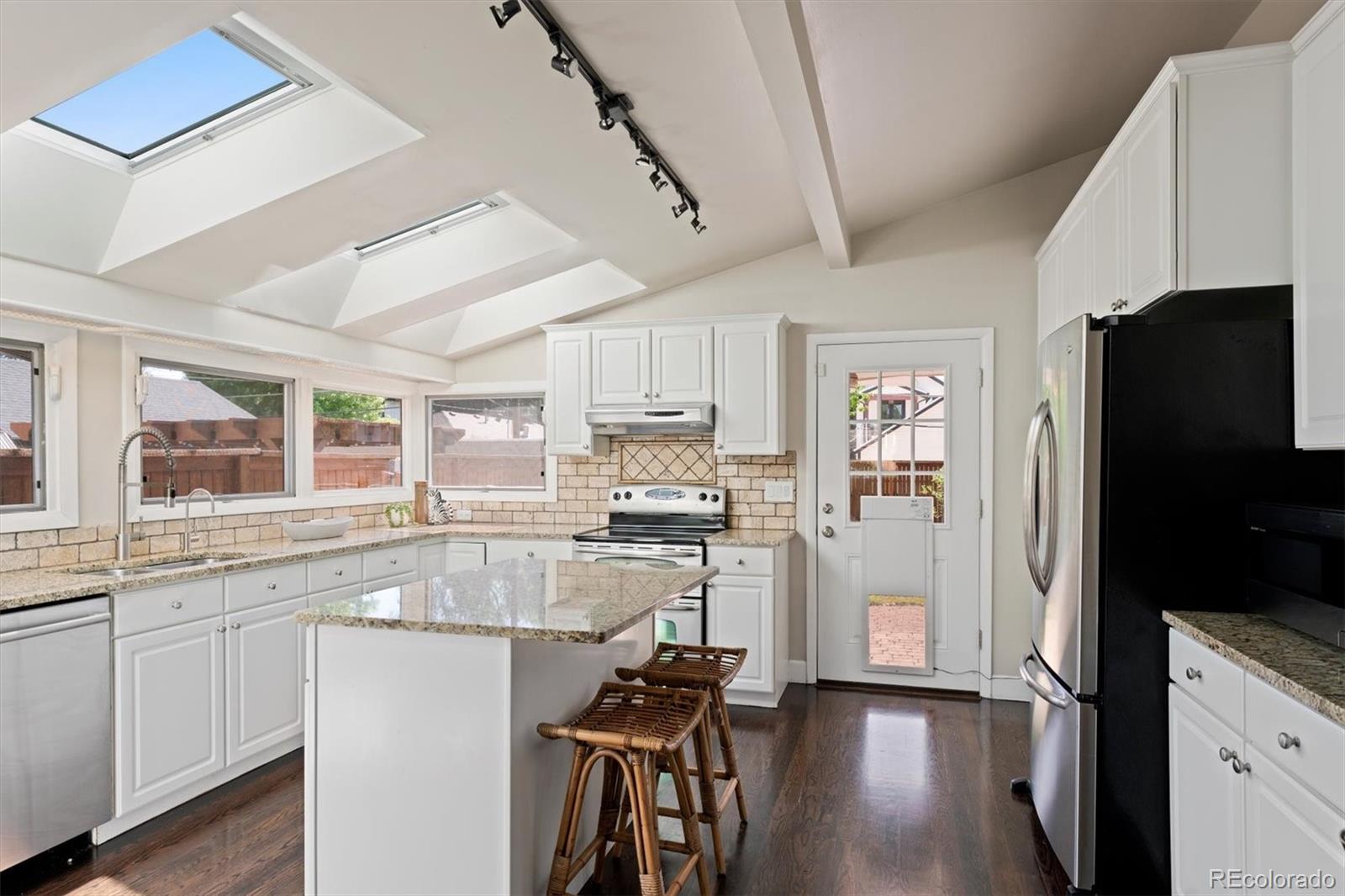 1643 South Ogden Street Denver, CO 80210 - Photo 10 of 39 a kitchen with kitchen island white cabinets and stainless steel appliances