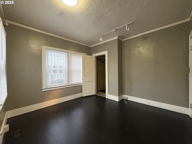 an empty room with wooden floor and windows with curtains