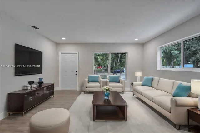 a living room with furniture flat screen tv and a large window