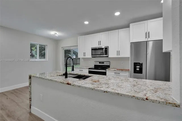 a large open kitchen with kitchen island a refrigerator a stove a sink and a wooden floors