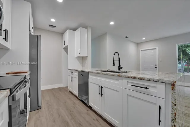 a kitchen with a sink stainless steel appliances and white cabinets
