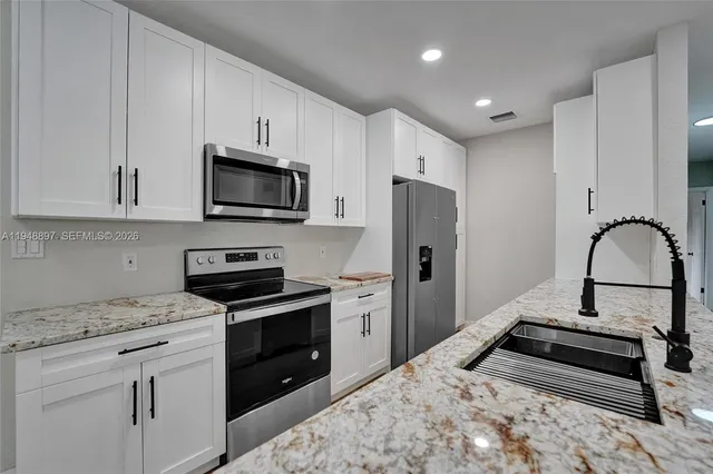 a kitchen with stainless steel appliances granite countertop a refrigerator stove and microwave