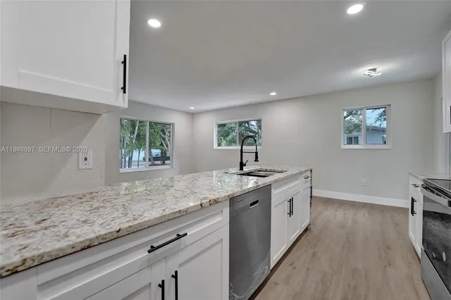 a kitchen with stainless steel appliances granite countertop a stove a sink and a microwave