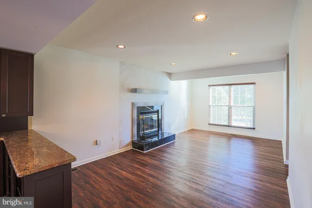an empty room with wooden floor fireplace and windows