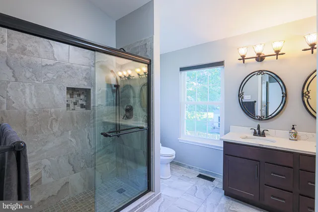 a bathroom with a double vanity sink toilet mirror and shower