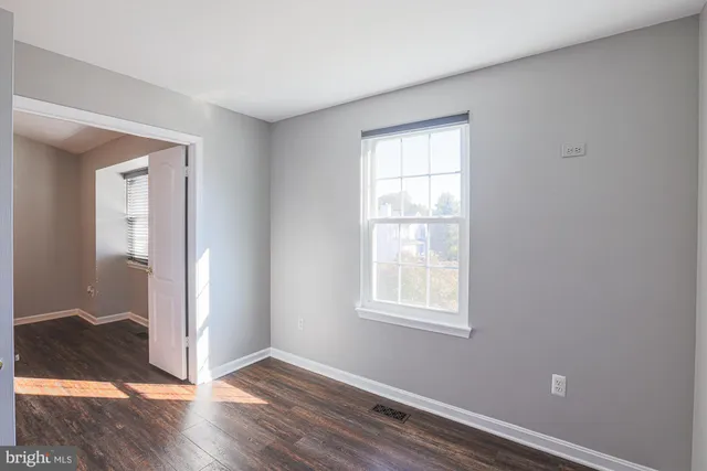 an empty room with wooden floor closet and windows