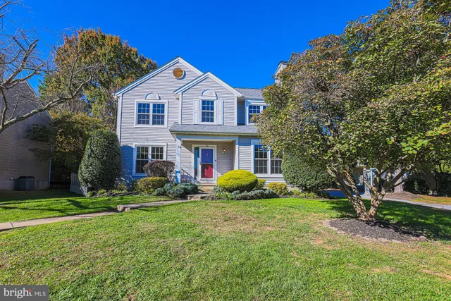 a front view of a house with garden and trees