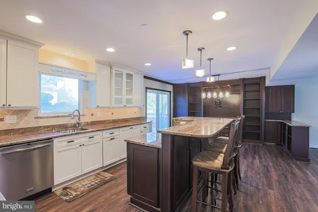 a kitchen with granite countertop a table chairs sink and wooden floor