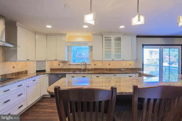 a kitchen with a stove a sink dishwasher a dining table and chairs with wooden floor