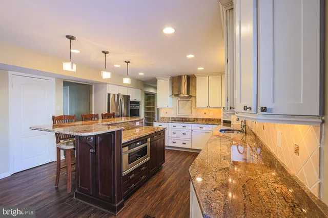 a large kitchen with wooden floor and stainless steel appliances