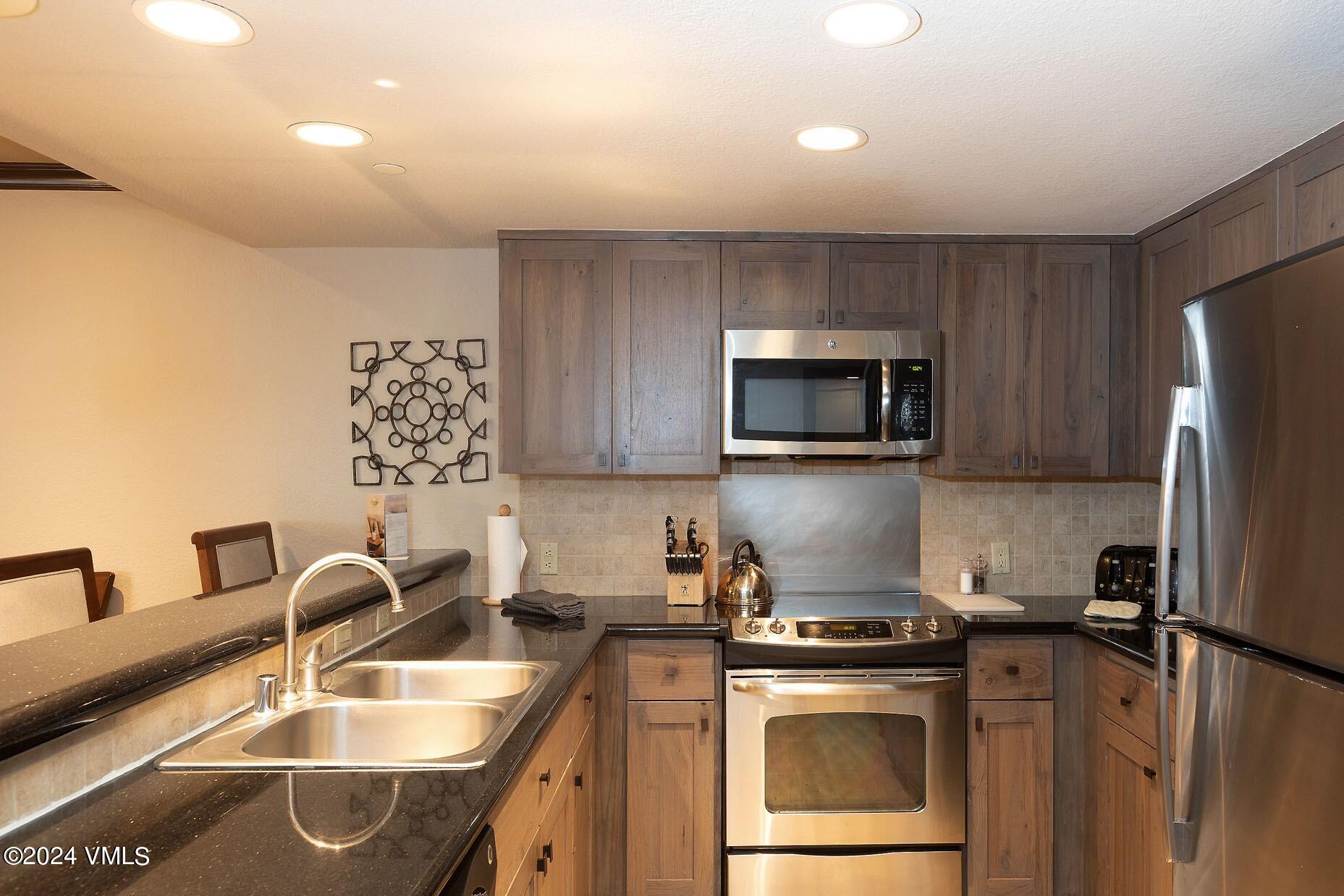 210 Offerson Road, Unit R215 WEEKS 13 & 14 Beaver Creek, CO 81620 - Photo 11 of 32 a kitchen with stainless steel appliances granite countertop a sink stove and refrigerator