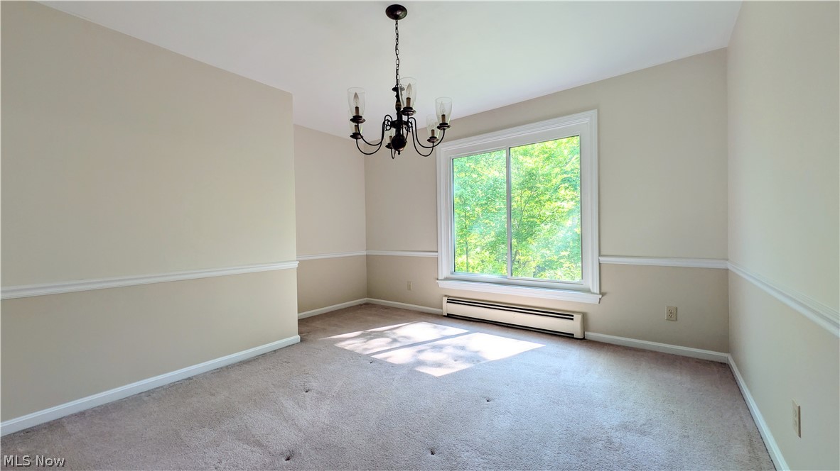 6409 Old Woods Road Ashtabula, OH 44004 - Photo 9 of 43 Carpeted dining room featuring a large window, a classic chandelier, and chair rail molding