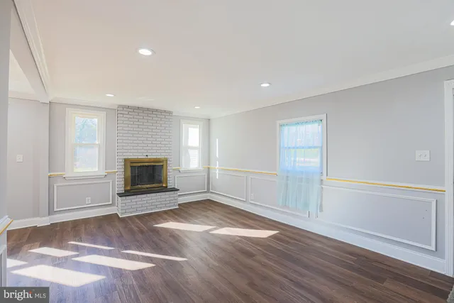 a view of empty room with wooden floor and fireplace
