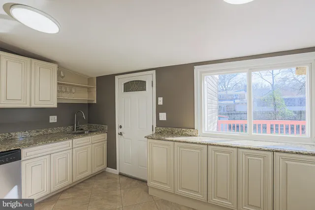 a kitchen with granite countertop a sink and a white cabinets