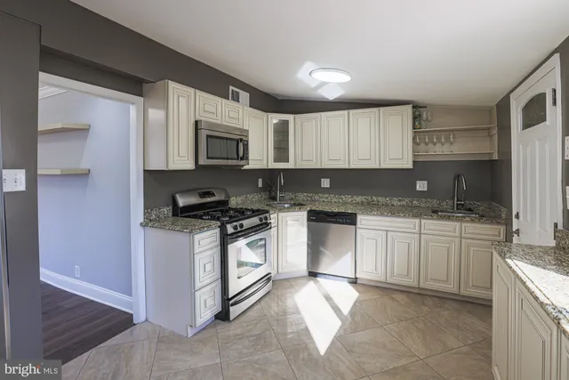 a kitchen with granite countertop a stove top oven microwave and cabinets