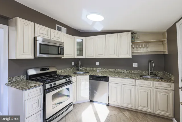 a kitchen with granite countertop white cabinets sink and stainless steel appliances