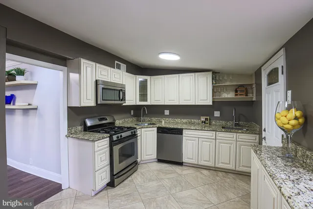 a kitchen with stainless steel appliances granite countertop a stove a sink and a microwave