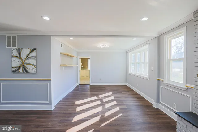 a view of an empty room with window and wooden floor