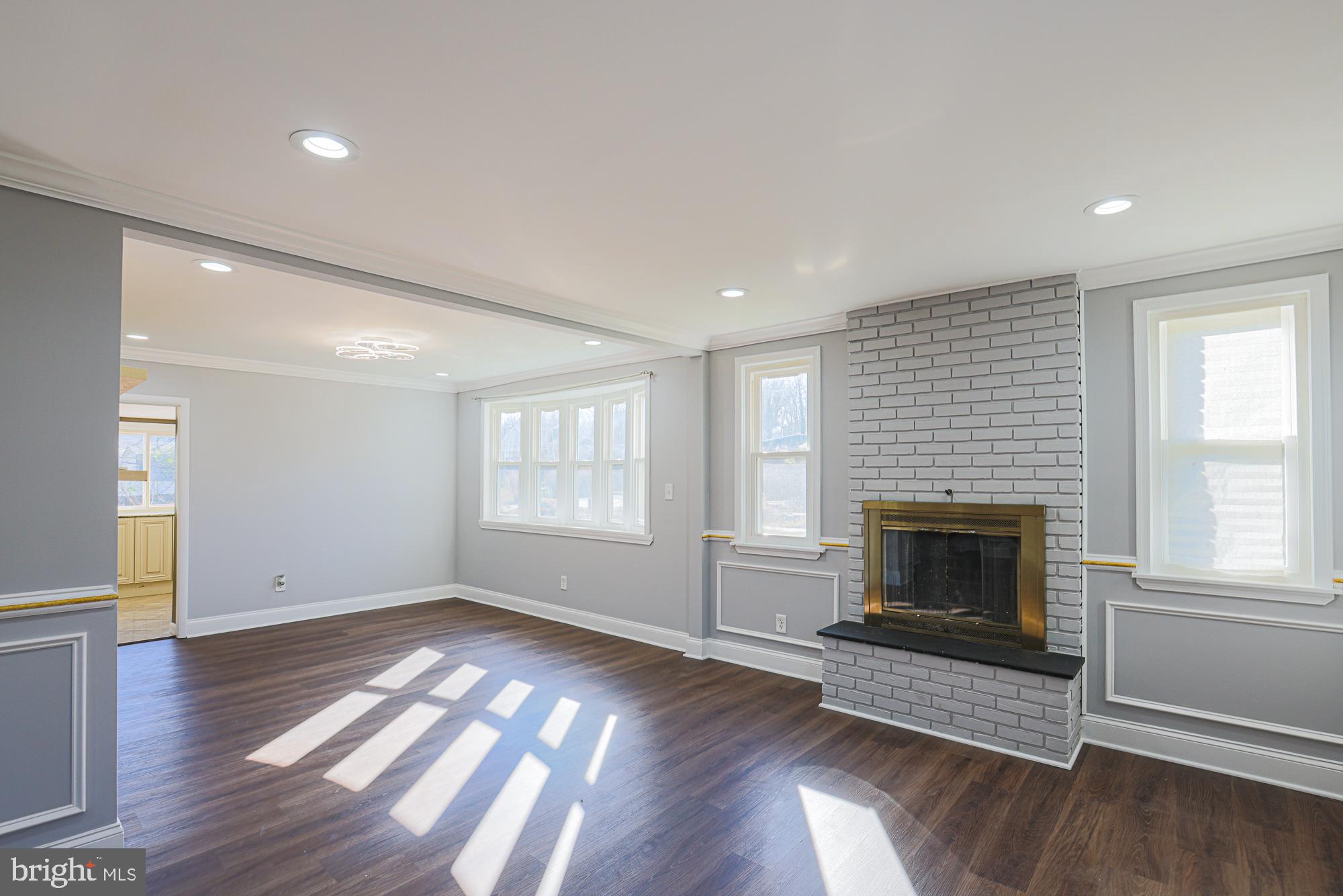 2507 Taney Road Baltimore, MD 21209 - Photo 10 of 58 an empty room with wooden floor fireplace and windows