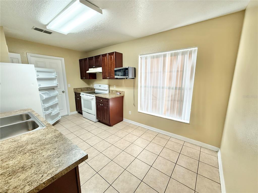 4695 Prairie Point Boulevard Kissimmee, FL 34746 - Photo 8 of 27 a kitchen with stainless steel appliances granite countertop a sink and a stove top oven