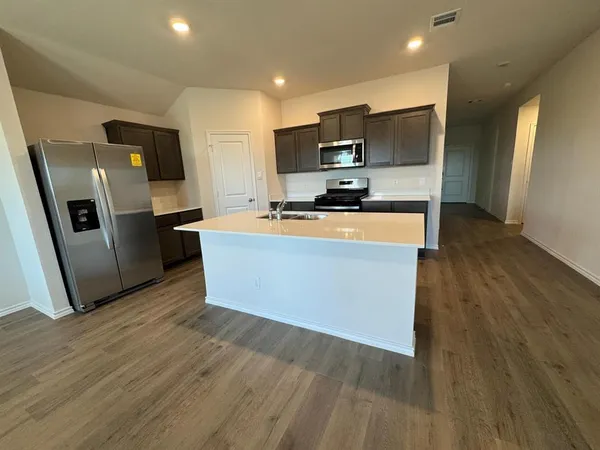 a kitchen with stainless steel appliances a refrigerator a stove top oven a sink and dishwasher