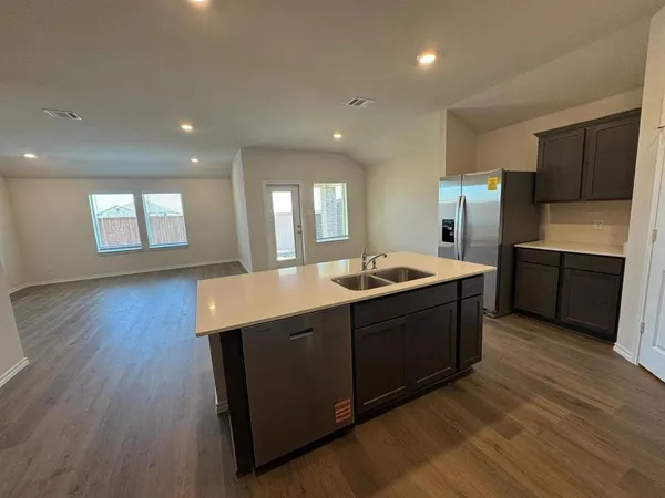 a large kitchen with stainless steel appliances granite countertop a large counter top a wooden floors and a large window